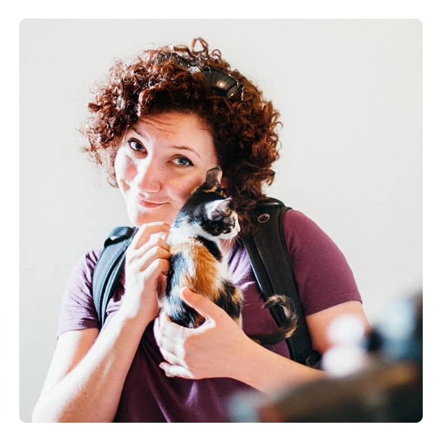 Woman with curly hair cuddling a small calico kitten